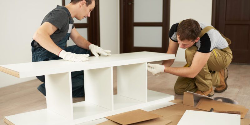 Two carpenters assembling furniture in house